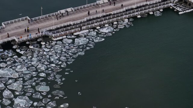Aerial view of the Sopot Pier contrasts with the dark Baltic sea water and the floating ice floes along the pier, Sopot, pomorskie, Poland.