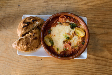 Shakshuka dish on wooden table with grilled bread