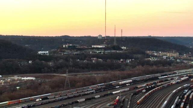 Aerial view of a vast container yard with rows of colorful containers, tracks, and trains under a soft sunset sky, Cincinnati, Ohio, United States.