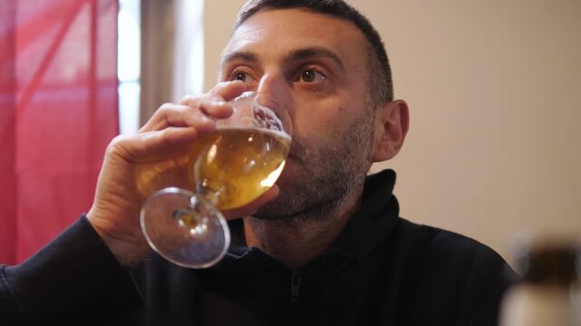 Young man sitting in pizzeria drinking a glass of beer. Relaxed lifestyle scene showing leisure time, social atmosphere and casual dining experience.