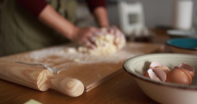Woman kneading dough for homemade cake with eggs - Handmade food, bakery and preparation concept - Focus on eggs and wooden rolling pin