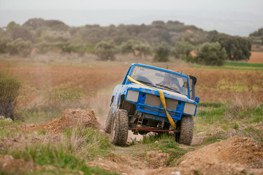 Blue off-road vehicle navigating challenging dirt terrain