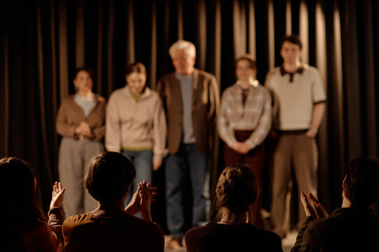 Audience applauding diverse amateur performers during standup stage presentation, representing live entertainment and public speaking. Useful for event promotion, comedy marketing, medium shot
