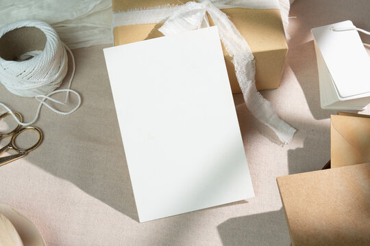 Mockup of a blank white greeting card on simple kraft paper gift boxes, with clipping path.