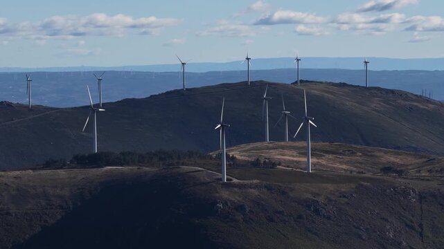Aerial view of wind turbines standing tall on rolling hills, a contrast of modern technology against the natural landscape, Amarante, Portugal.