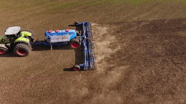 Ternopil, Ukraine - March 25, 2026: Aerial perspective of a tractor with a cultivator tilling brown soil in a field, showing distinct furrows and agricultural activity in the landscape