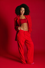 Fototapeta premium Young woman showcases bold red fashion statement in a vibrant setting with confident pose