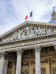 Obraz premium Panthéon pediment frieze and French flag with dramatic cloudy sky, Paris, France.