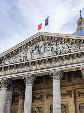 Panth&eacute;on pediment frieze and French flag with dramatic cloudy sky, Paris, France.