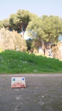 Vertical: Ten euro banknote lies on the ground, seemingly lost and forgotten. The scene highlights chance, loss, and unnoticed value in an everyday urban environment.
