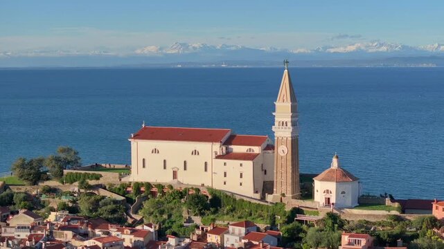 Aerial view of Piran with St. George Church and snowy Alps on background. Beautiful Coastal City in Slovenia