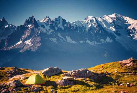 Tourist tent on a slope among snow-capped mountains that tower majestically in the distance. Location place Mont Blanc massif, Chamonix, France, Europe.