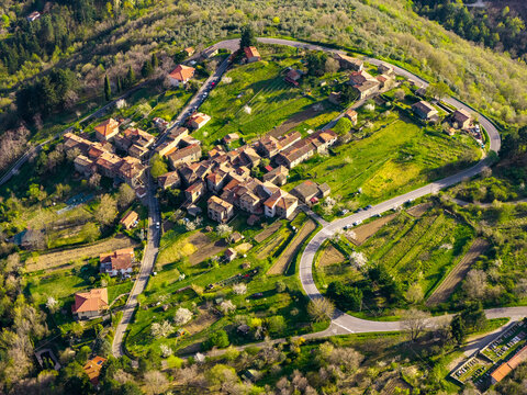 Aerial view of the historic stone village of Trappola surrounded by lush green hills and winding roads during spring in Trappola, Tuscany, Italy.