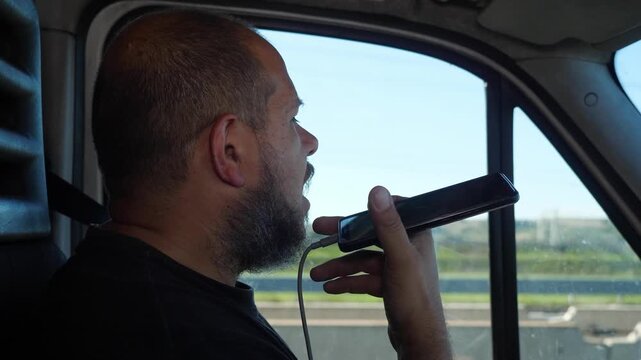 Delivery driver records a voice message while driving a van, showing dangerous behavior. The scene highlights distraction and road safety risks.