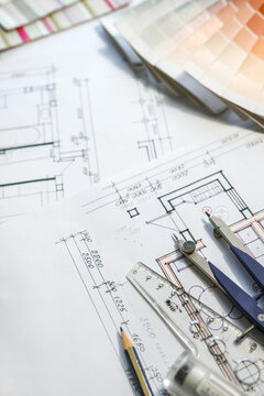 Architectural floor plan with interior design materials, color palette, fabric samples and drafting tools for home renovation project planning.