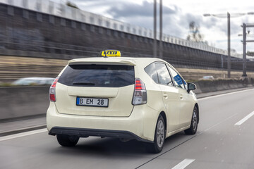 Hybrid taxi car driving on highway. Light beige vehicle with taxi sign moves along the road. © puhimec