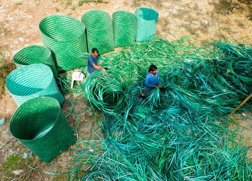Manikganj, Bangladesh - 15 January 2025: Aerial view of workers amidst a vibrant sea of green plastic, crafting and sorting, reflecting the ingenuity of local recycling efforts.