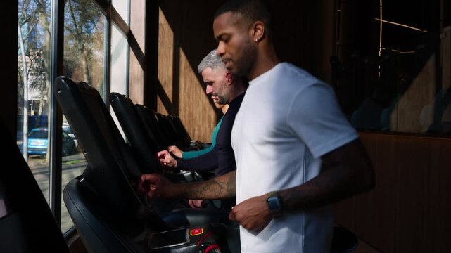Multiethnic men running on treadmills during gym workout
