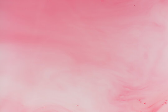 Light pink ink flow in water creating soft abstract shapes
