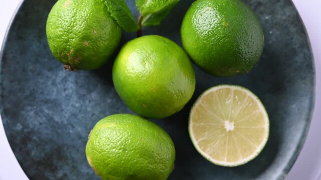 Rotating fresh limes on black plate. Close up