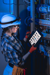 Female engineer managing electrical system with tablet near switchboard. Electrical inspection.