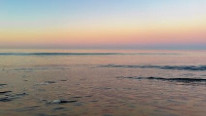 Fototapeta premium Macro shot of water on the beach during twilight. Focus on wet sand texture.