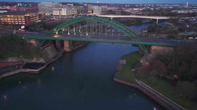 Aerial telephoto shot climbing over the River Wear at dawn, showing the Wearmouth Bridge and Monkwearmouth Railway Bridge with the new Keel Crossing in the background.