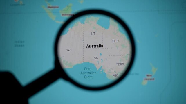 Map of Australia under magnifying glass shows states and geography. Tasmanian links continent scale new zealand proximity, ocean routes, desert landscape, economy relationship.6+