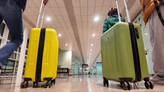 Family walking through an airport terminal with luggage, child and parents leaving for vacation, low-angle view of travelers with suitcases and bags ready for a journey