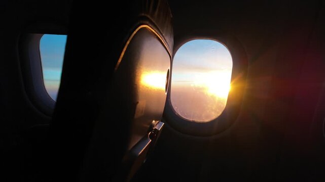 Morning sunlight streaming through an airplane window during a flight above the clouds, revealing an empty passenger seat and a breathtaking sunrise from the sky