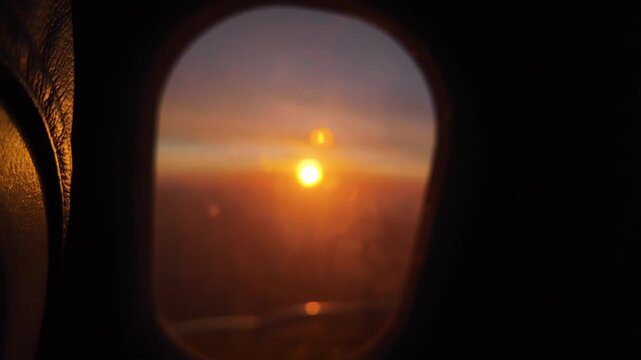 Breathtaking airplane window view of the golden sun rising above the horizon with beautiful lens flare, offering a sense of freedom, travel, and new beginnings