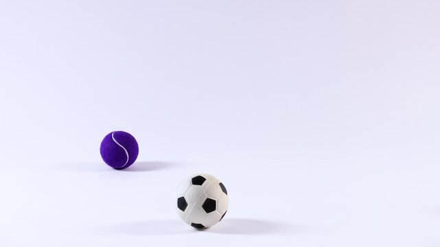 Colorful rubber and tennis balls dynamically bounce and fall onto a clean white surface in a playful and energetic motion sequence.