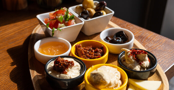 Breakfast appetizer snacks including cheese, hummus, pickled olives