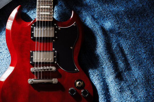 Electric red sg guitar on blue plaid. Music rock background in the day light