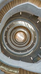 Fototapeta premium Top view of multi level spiral staircase with wooden steps and concrete walls. Design creates a mesmerizing geometric pattern and sense of depth. Ideal for architectural and design themes.