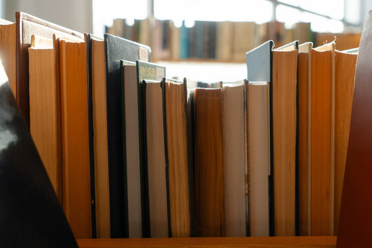 Old books on the bookshelf in library archive interior in sunny day. Shallow depth of field