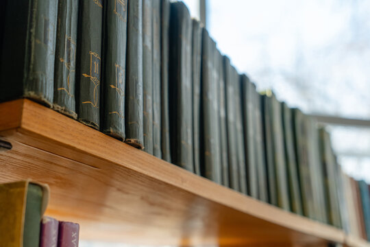 Old books on the bookshelf in library archive interior in sunny day. Shallow depth of field