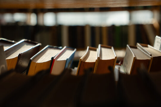 Old books on the bookshelf in library archive interior in sunny day. Shallow depth of field