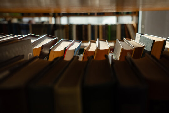Old books on the bookshelf in library archive interior in sunny day. Shallow depth of field