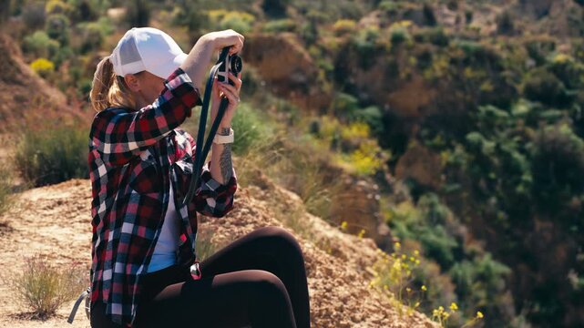 Female traveler sit alone on cliff overlook canyon, hold vintage camera while reflecting on life.Concept of self discovery, inner thoughts, emotional balance, freedom,personal transformation in nature