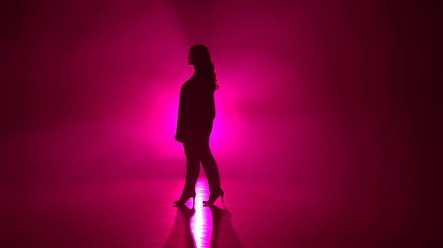 Silhouette of a confident woman walking in a foggy environment illuminated by pink lights. Represents empowerment and self-expression in modern fashion