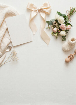 Neutral baby flatlay background with ribbon roses bootie and blank card for newborn announcement and baby shower invitation design