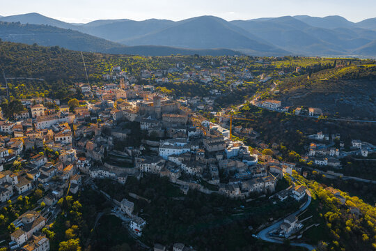 Aerial view of the historic Castello Piccolomini and stone houses of the hilltop village surrounded by green mountains in Capestrano, Abruzzo, Italy.