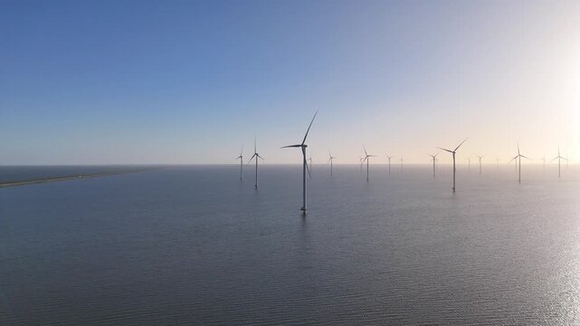 Wide aerial perspective showing the distant dyke as a thin line beside the wind farm.