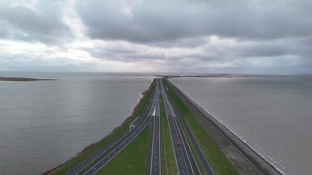 Drone descends from high altitude toward the roadway while vehicles pass below beneath a textured cloudy sky.