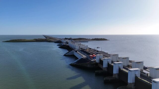 Slow lateral drone move across the lock works with passing cars construction areas and the long dam fading away.