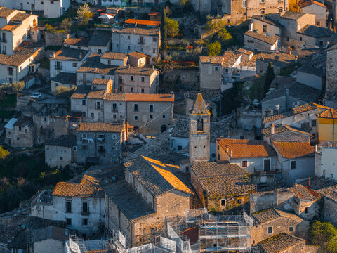Aerial view of the historic stone buildings and church tower of the medieval village under warm sunlight Capestrano, Abruzzo, Italy.