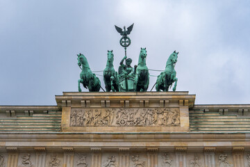 Obraz premium Brandenburg Gate in Berlin with a bronze classical two‑wheeled chariot atop, driven by the goddess Victoria, symbolizing peace and triumph, one of Germany’s iconic symbols.Berlin,Germany.
