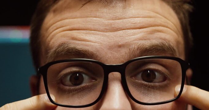 Close-up of a man adjusting his glasses while struggling to see clearly, indicating poor vision, wrong prescription, or need for new eyewear.