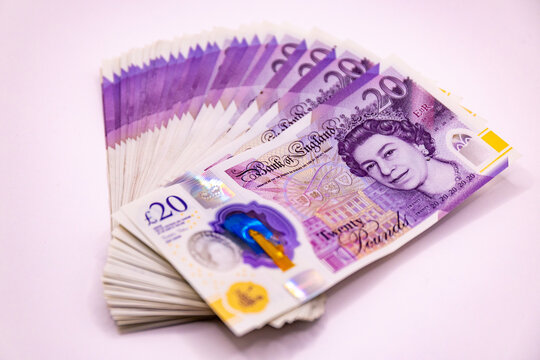 A stack of twenty pound banknotes from the Bank of England featuring Queen Elizabeth II, isolated on white background